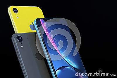Product shot of iPhone XR blue and yellow on black background Editorial Stock Photo