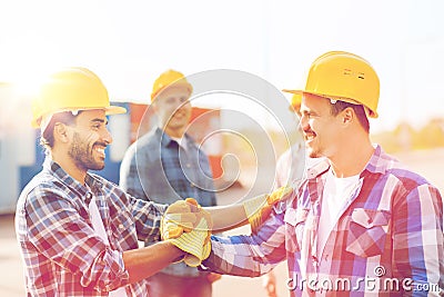 Group of smiling builders in hardhats outdoors Stock Photo