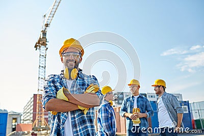 Group of smiling builders in hardhats outdoors Stock Photo