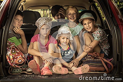 Group of smiling children big family in car trunk luggage going to road trip in family car symbolizing kids friendship and happy c Stock Photo