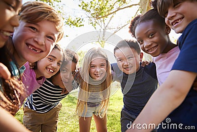 Group of smiling schoolchildren lean in to camera embracing Stock Photo