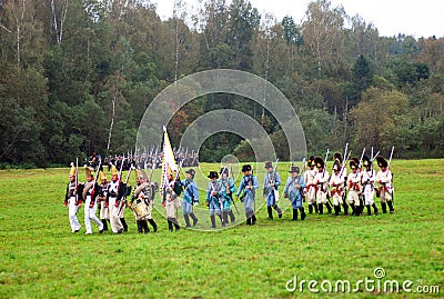 A group of soldiers-reenactors march with a flag. Editorial Stock Photo