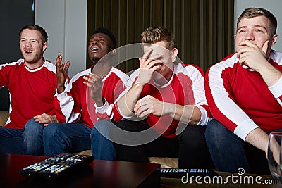 Group Of Sports Fans Watching Game On TV At Home Stock Photo
