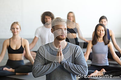 Group of sporty people in Lotus exercise with male instructor Stock Photo