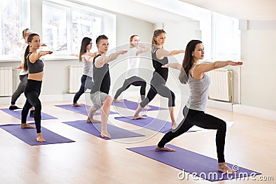 Group of sporty people practicing yoga with instructor, Warrior Stock Photo