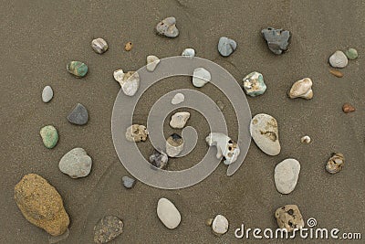 Group of stones of different colors and textures on an empty beach during the day Stock Photo