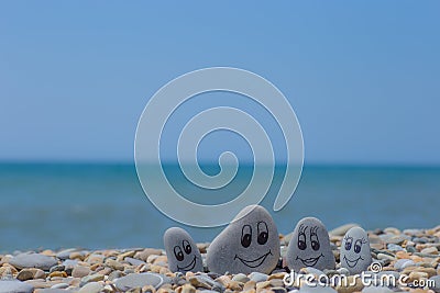Group of stones with drawn faces in the sand. Father, mother, daughter and son. Concept of happy family Stock Photo