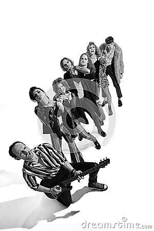 Group of stylish people, man and woman, rock music performers posing over white background. Black and white image. Top Stock Photo