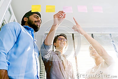 Group of successful Asian businessmen teamwork. Brainstorm meeting with sticky paper notes on the glass wall for new ideas. Stock Photo