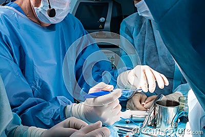 A group of surgeons performing minimally invasive surgery on the patient's anus using surgical instruments Stock Photo