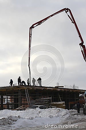 Group team of builders working on the construction of the building in the winter pour concrete with special construction equipment Editorial Stock Photo