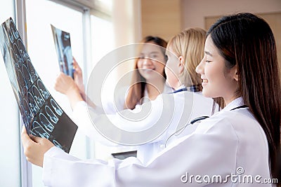 Group of team doctors examining x-ray film about skull and skeleton of patient for checking disease while discussion. Stock Photo