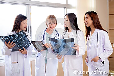 Group of team doctors examining x-ray film about skull and skeleton of patient for checking disease while discussion. Stock Photo