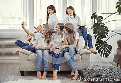 Group of teenage girls is making a selfie. Kids with phones, tablets and headphones. Stock Photo