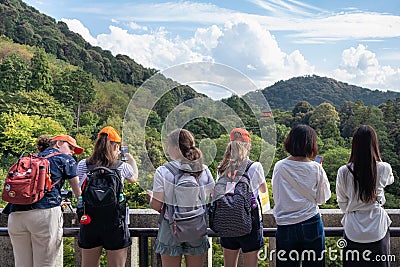 Group of teenager girls taking pictures of a Japanese pagoda with smartphones. Wearing red caps and complements, same color as the Editorial Stock Photo