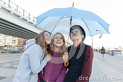 Group of teenagers friends having fun in the city, laughing kids with umbrella. Urban teen lifestyle Stock Photo