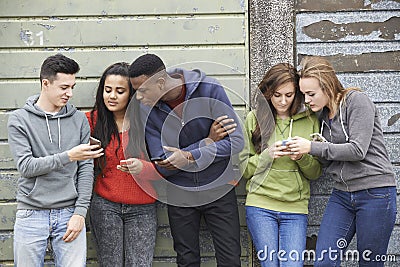 Group Of Teenagers Sharing Text Message On Mobile Phones Stock Photo