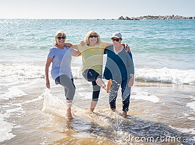 Group of three senior women walking having having fun on beach. Friendship and retirement lifestyle Stock Photo