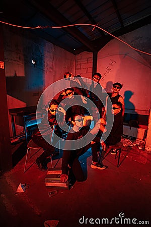 a group of thugs wearing dark clothes and glasses were having fun chatting with their friends in an old building Stock Photo