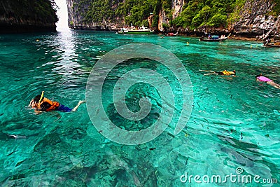 Group of Tourism on trip in life jacket with diving mask is snorkeling among many Indo- Pacific sergeant fish Stock Photo