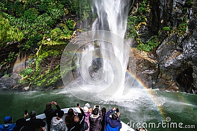 A group of tourists enjoying a stunning scene of nature while cruising into waterfall in Milford Sound, New Zealand. I Editorial Stock Photo