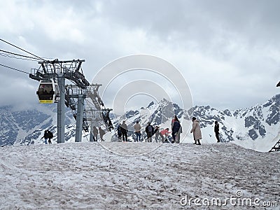 A group of tourists stands on the mountain at the lift and is photographed and admires the beautiful views of the snowy mountains Editorial Stock Photo