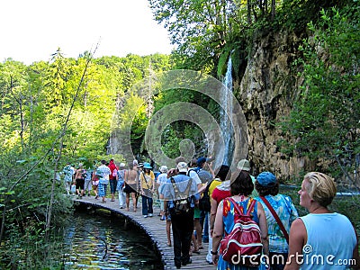 A group of tourists walking along a narrow path next to the insanely beautiful blue lake. Plitvice, Croatia- July 22, 2010 Editorial Stock Photo