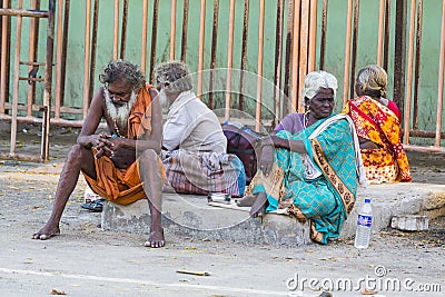 A Group of unidentified Sadhus pilgrims dressed in orange clothes, sitting in the street, on the road, waiting for food. It is a m Editorial Stock Photo