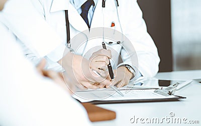 Group of unknown doctors are sitting at the desk and discussing medical treatment, using a clipboard, close-up. Team of Stock Photo