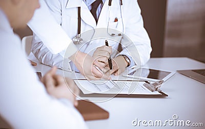 Group of unknown doctors are sitting at the desk and discussing medical treatment, using a clipboard, close-up. Team of Stock Photo