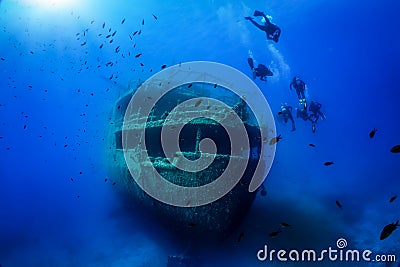 A group of unrecognizable divers explore a sunken shipwreck Stock Photo