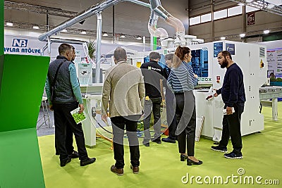 A group of visitors and an engineer discuss the operation of woodworking equipment Editorial Stock Photo