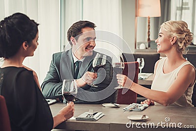 Group of wealthy people clinking glasses of red wine in restaurant Stock Photo