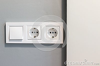 Group of white european electrical outlets and a switch located on a gray wall Stock Photo