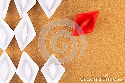 A group of white paper ship pointing in one direction and one red paper ship. Business behind an innovative solution concept Stock Photo
