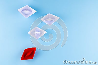 A group of white paper ship pointing in one direction and one red paper ship. Business behind an innovative solution concept Stock Photo