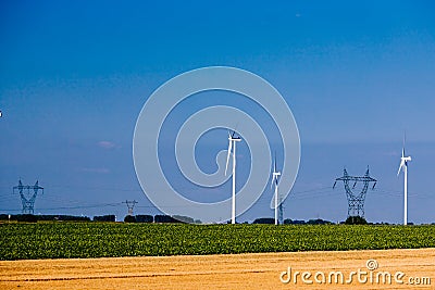 Group of windmills for renewable electric energy production and pylon Stock Photo