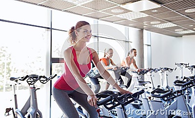 Group of women riding on exercise bike in gym Stock Photo