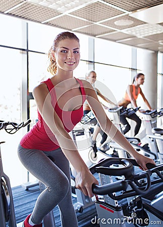 Group of women riding on exercise bike in gym Stock Photo