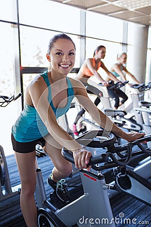 Group of women riding on exercise bike in gym Stock Photo
