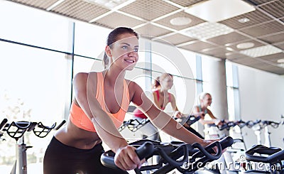 Group of women riding on exercise bike in gym Stock Photo