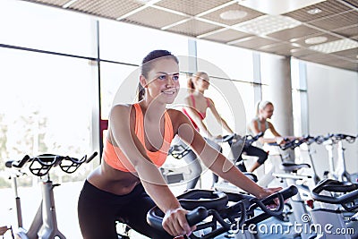 Group of women riding on exercise bike in gym Stock Photo