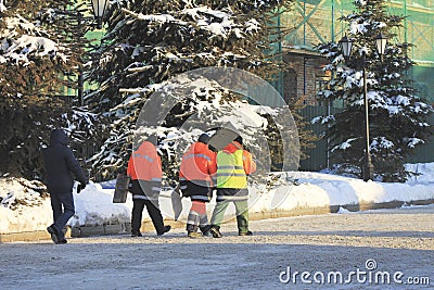 Group of workers with shovels in overalls walking on winter snow-covered street in the city Editorial Stock Photo