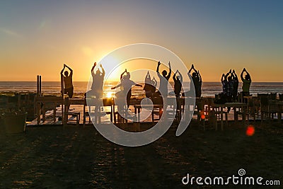 Group doing yoga exercises on the beach at sunset Editorial Stock Photo