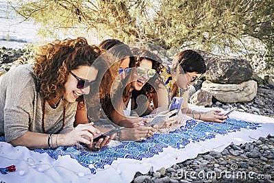 Group of young adult women use modern phones together having fun and laughing a lot - happy females people enjoying technology and Stock Photo