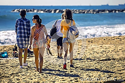 Group of young and attractive people is going along the sandy beach. Stock Photo