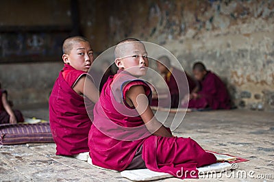 Two Bhutanese young novice monk turn their head to look you when during study , Bhutan Editorial Stock Photo
