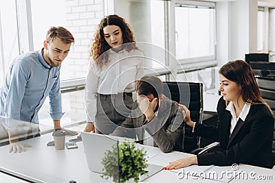 Group of young business partners working in modern office. Coworkers having trouble while working on laptop Stock Photo