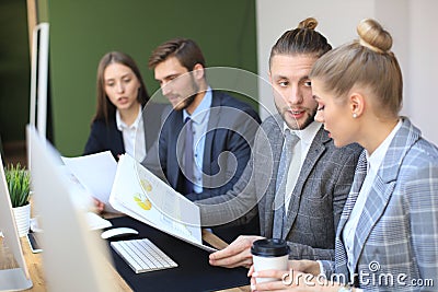 Group of young business people working, communicating while sitting at the office desk together with colleagues Stock Photo