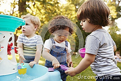 Group Of Young Children Playing With Water Table In Garden Stock Photo